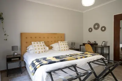 a bedroom with a large white bed with pillows at Penguino Guesthouse in Hermanus