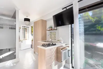 a kitchen with a stove and a tv on the wall at Blouberg Studio Apartment in Bloubergstrand