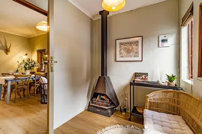 a living room with a fireplace and a table at Villa Helderberg in Somerset West