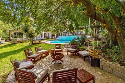 a patio with a bunch of chairs and a tree at Villa Helderberg in Somerset West