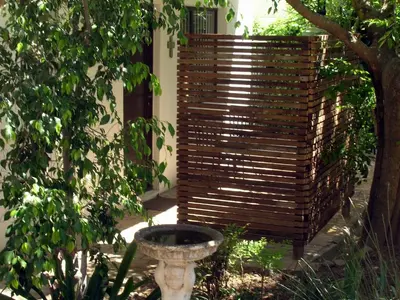 a wooden privacy fence next to a tree in a yard at 16 Rhodes-North Self Catering Apartment & Studio in Stellenbosch