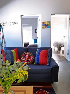 a blue couch with colorful pillows in a living room at 16 Rhodes-North Self Catering Apartment & Studio in Stellenbosch