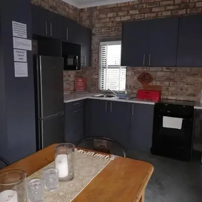 a kitchen with blue cabinets and a wooden table at 16 Rhodes-North Self Catering Apartment & Studio in Stellenbosch
