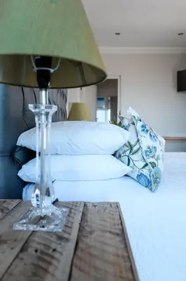 a bed with a lamp on a wooden table at Hilltop Guesthouse in Bellville