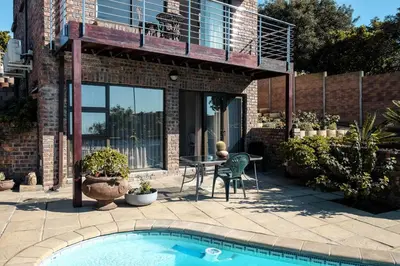 a patio with a table and a swimming pool at Hilltop Guesthouse in Bellville