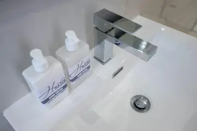 a bathroom sink with two bottles of soap on it at Hilltop Guesthouse in Bellville