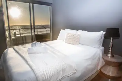 a bedroom with a white bed with a large window at Spacious Luxury 3 Bedroom Apartment B401 Sea Spray in Bloubergstrand