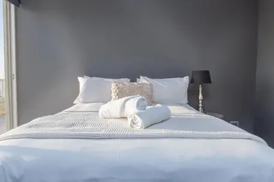 a white bed with towels on top of it at Spacious Luxury 3 Bedroom Apartment B401 Sea Spray in Bloubergstrand