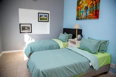 two beds in a room with blue walls at Relaxing Guest House in th Heart of Ndabeni in Cape Town