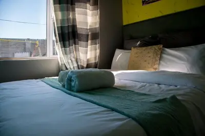 a bed with a blue blanket and a window at Relaxing Guest House in th Heart of Ndabeni in Cape Town
