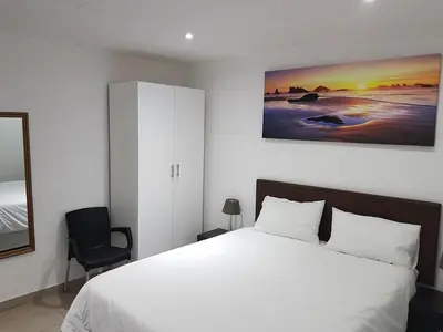 a bedroom with a white bed and a painting on the wall at Relaxing Guest House in th Heart of Ndabeni in Cape Town