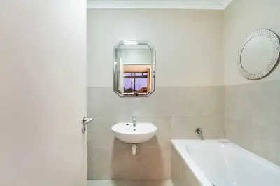 a white bathroom with a sink and a mirror at Waterstone East F201 in Cape Town