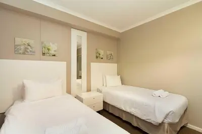 two beds in a room with white sheets at Waterstone East F201 in Cape Town