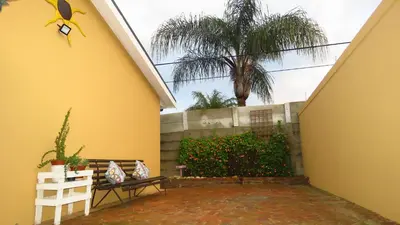 a yellow house with a bench and a palm tree at Sonvanger 2 in Paarl