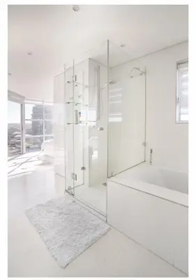 a white bathroom with a glass shower and a tub at Designer Flat with scenic views in Cape Town