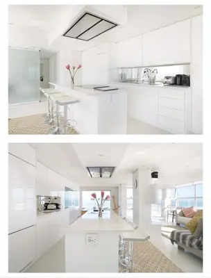 a white kitchen with white cabinets and a table at Designer Flat with scenic views in Cape Town