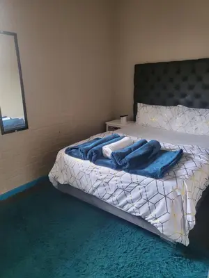 a bedroom with a bed with a blue blanket on it at MJ ACCOMODATION in Cape Town