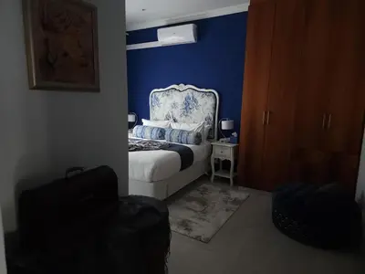 a bedroom with a bed with a blue wall at Perhethian in Cape Town