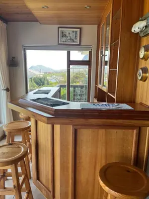 a kitchen with a bar with stools and a window at Jocks Place (on the sea) in Bettyʼs Bay