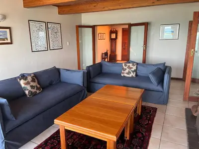 a living room with blue couches and a coffee table at Jocks Place (on the sea) in Bettyʼs Bay