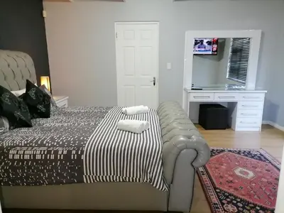 a bedroom with a bed and a desk with a television at 20 On Percy in Cape Town