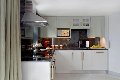a kitchen with white cabinets and black counter tops at No. 2 The Yard in Franschhoek