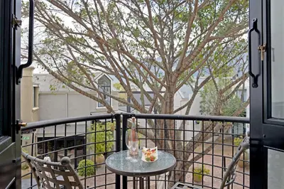 a table and chairs on a balcony with a tree at No. 2 The Yard in Franschhoek