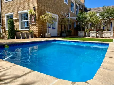 a blue swimming pool in front of a house at Mountainview Guesthouse in Cape Town