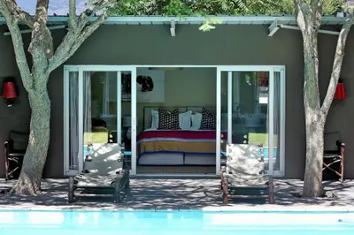 a bedroom with a bed and two chairs next to a pool at The Library in Franschhoek