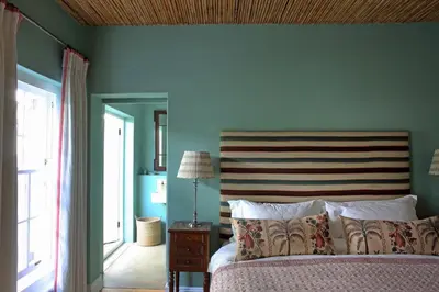 a bedroom with a bed and a blue wall at Tugela in Franschhoek