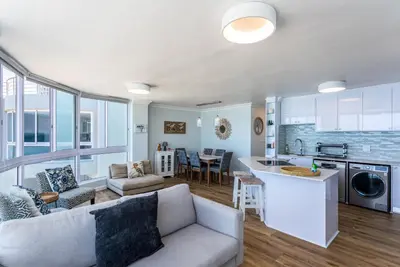 a kitchen and a living room with a couch and a table at Ocean View A1101 by CTHA in Bloubergstrand