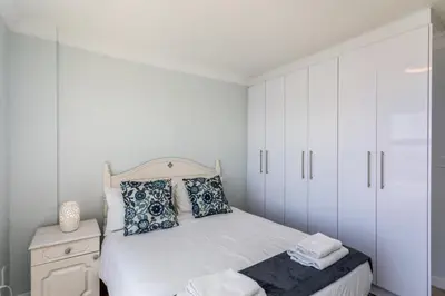 a white bedroom with a bed and white cabinets at Ocean View A1101 by CTHA in Bloubergstrand