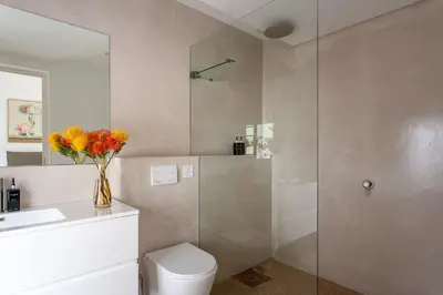 a bathroom with a shower and a toilet and a vase of flowers at Minserie Collection in Stellenbosch
