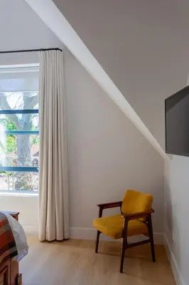 a bedroom with a yellow chair and a window at Minserie Collection in Stellenbosch