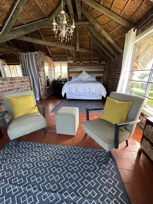 a bedroom with a bed and two chairs and a chandelier at Hemel in Hermanus Three bedroom Home in Hermanus