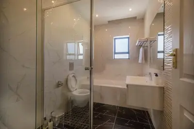 a bathroom with a shower and a toilet and a sink at Oceanway Boutique Hotel/Conference in Cape Town