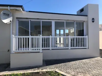 a white house with a balcony with glass doors at 147 Abalone-Inn in Hermanus