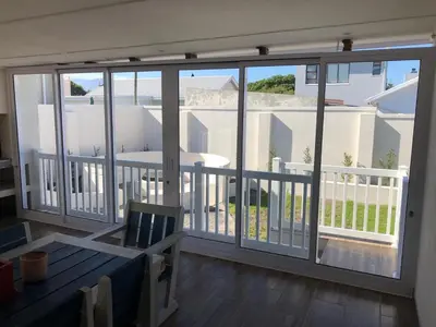 a balcony with large sliding glass doors and a table at 147 Abalone-Inn in Hermanus