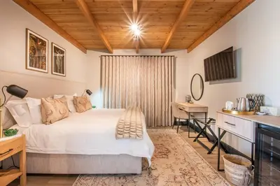 a bedroom with a bed and a desk and a table at Eikenhof Estate in Brackenfell