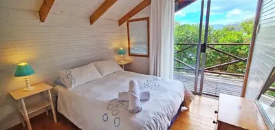 a bedroom with a white bed and a large window at Little Haven 10 & 12 in Hermanus