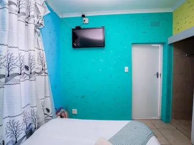 a bedroom with a blue wall with a tv on the wall at Relaxing guest House in the heart of Ndabeni in Cape Town