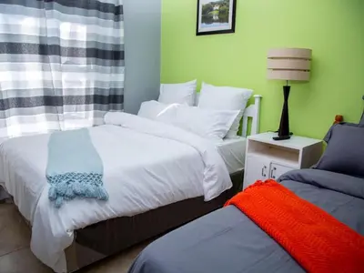 a bedroom with two beds and a lamp on a table at Relaxing guest House in the heart of Ndabeni in Cape Town