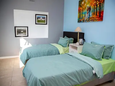 two beds in a bedroom with a painting on the wall at Relaxing guest House in the heart of Ndabeni in Cape Town