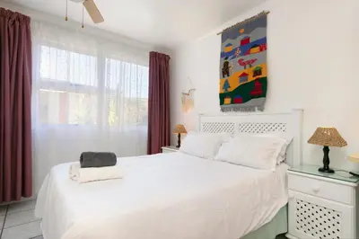 a bedroom with a white bed and a window at The Bohemian Guesthouse in Cape Town