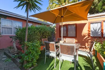 a table and chairs under an umbrella in a yard at The Bohemian Guesthouse in Cape Town