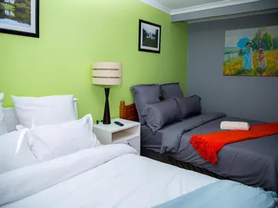 a bedroom with two beds and a couch at Relaxing guest House in The heart of Ndabeni in Cape Town