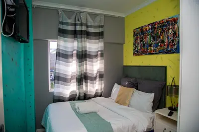 a bedroom with a bed and a painting on the wall at Relaxing Guest House in the heart of Ndabeni in Cape Town