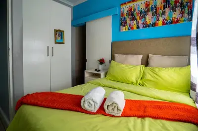 a bedroom with a green bed with towels on it at Relaxing Guest House in the heart of Ndabeni in Cape Town