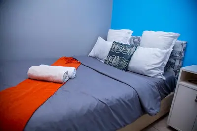 a large bed with colorful pillows on top of it at Relaxing Guest House in the heart of Ndabeni in Cape Town