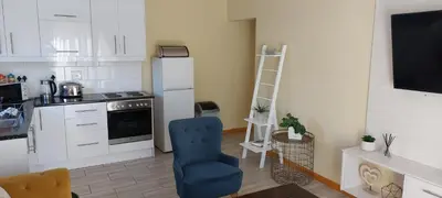 a kitchen with a blue chair and a refrigerator at Shalom Self catering in Cape Town